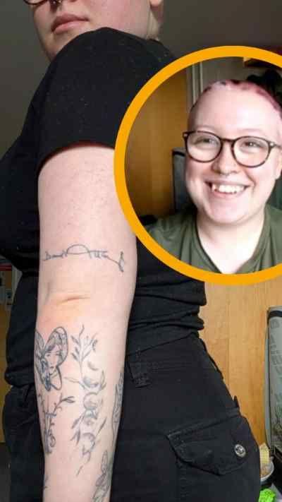 The arm of a tattooed person with butterflies and plants and the signature of Sir David Attenborough