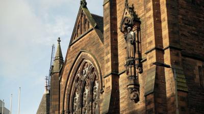 Dealbh de dh' Eaglais Chaluim Chille ann an Glaschu air là soilleir, le sgòthan gheal san adhar.