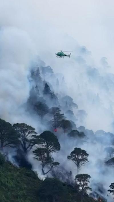 A helicopter flying over a wildfire in the Cairngorms