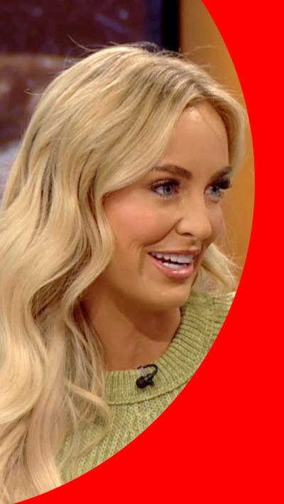 Leanne Quigley smiles on the BBC Breakfast sofa. She has wavy long blonde hair and wears a green woolly jumper 