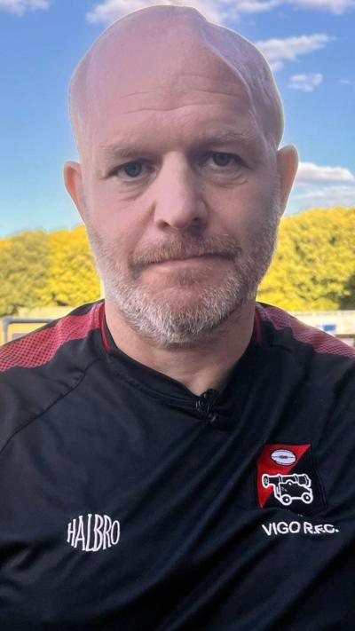 Close up middle aged balding man with greying beard outdoors wearing black rugby top 