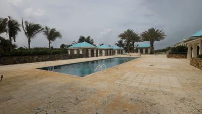 A swimming pool surrounded by blue pavilions and palm trees. 