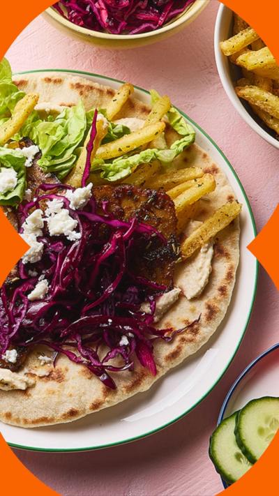 A top-down photos of a tofu gyros surrounded by plates of ingredients