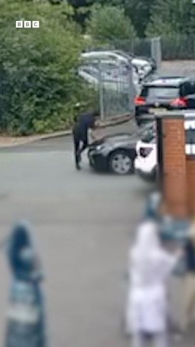 A man in black shirt and trousers with his hand on a car bonnet moments before he was knocked over