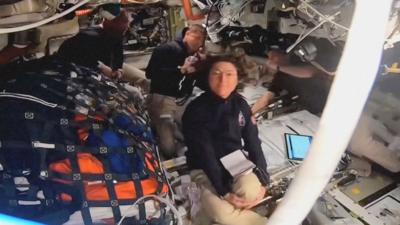 Four astronauts are seen in their spaceship.