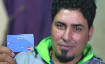 Man holds a credit card up to the camera