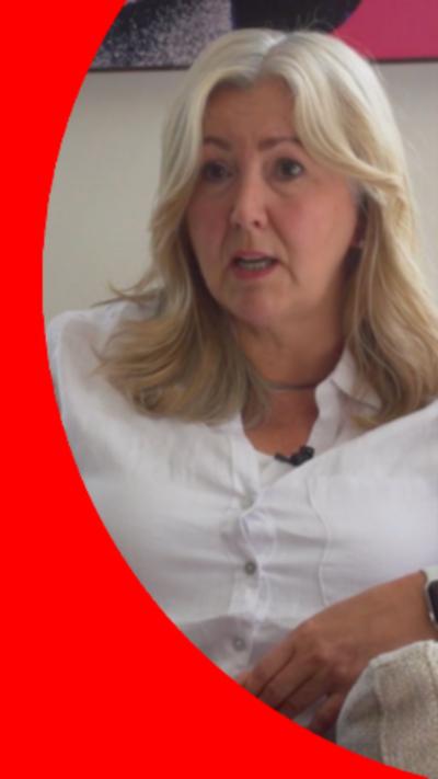 A woman with long blonde hair wearing a white shirt.
