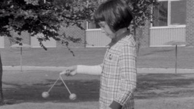 A girl playing with a set of clackers.