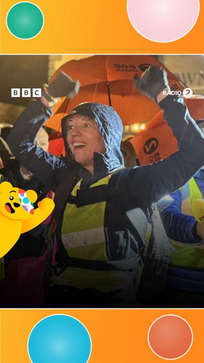 Sara Cox raises her arms in the air.