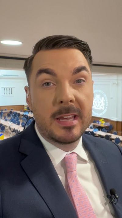 Reporter wearing suit and tie talks into camera.