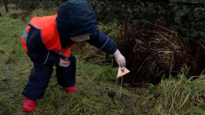 Gille òg a' comharrachadh salachar chor le bratach