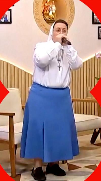 A nun wearing a blue skirt and white shirt, beatboxing into a microphone