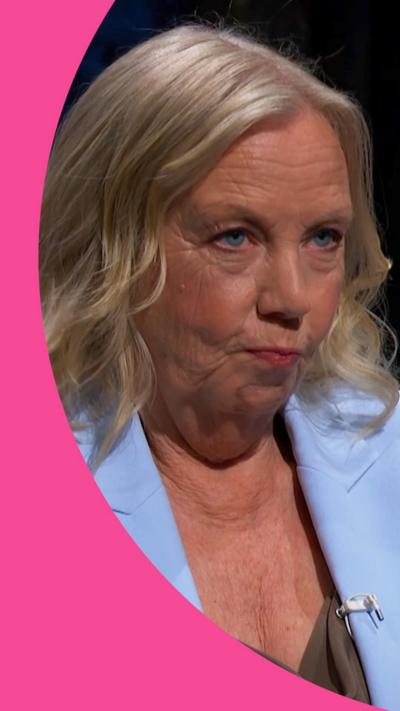 A woman, Deborah Meaden, has blonde hair and wears a blue jacket. Her lips are pursed.