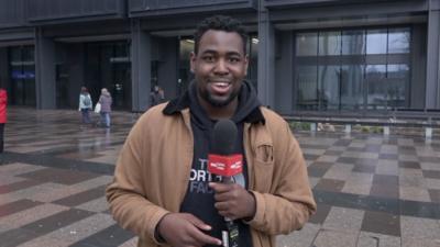 Terel Edmunds holds a microphone on a wet Cardiff street