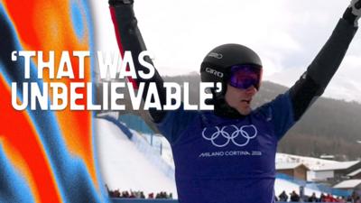 A snowboarder in mid-air performing a trick over a jump on a snow-covered mountain course.