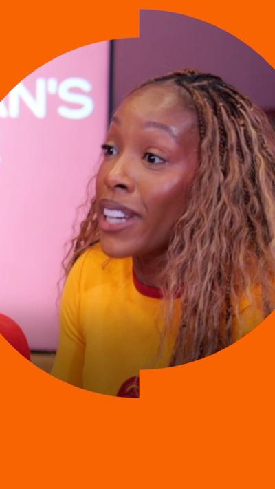 Woman wearing glasses and headphones in front of red microphone looking towards another woman wearing a yellow t-shirt in front of a similar microphone.