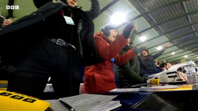 Dealbh a' sealltainn luchd-aithris BBC Radio nan Gàidheal a' dèanamh gàirdeachas aig Hampden