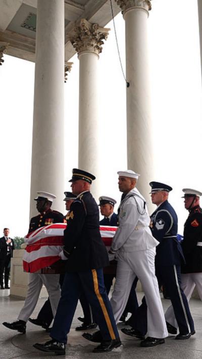 Members of military carrying casket draped in US flag
