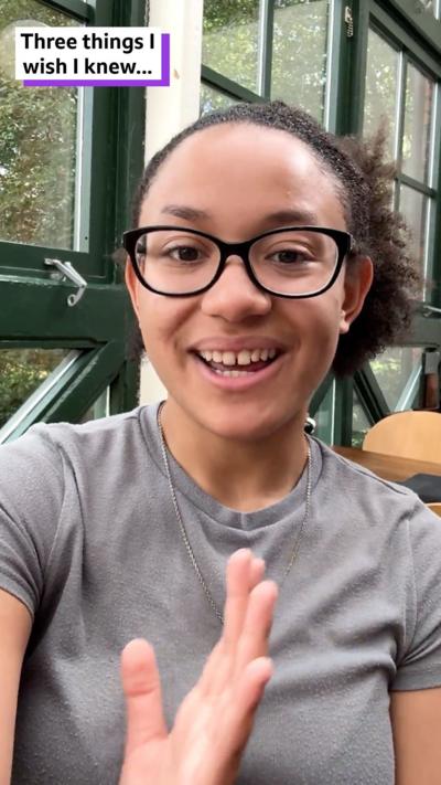 Malaya, a smiley teenager, sits in a cafe.