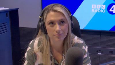 Dame Laura Kenny in front of a mic wearing headphones