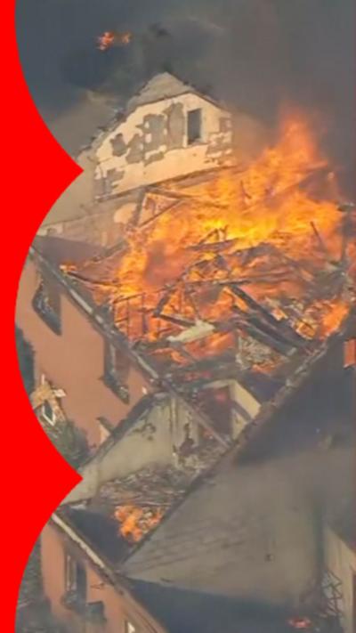 Aerial image of a building with orange flames ripping through the roof.