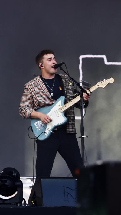 Sam Fender holds a blue electric guitar and performs at Glastonbury 2022