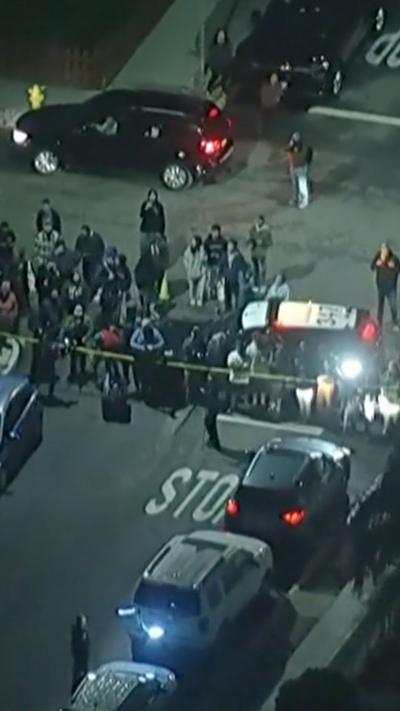 An aerial view of a group of people standing behind a police cordon.