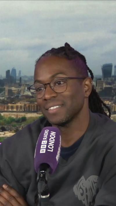 TV presenter Nigel Clarke sits in front of a purple Radio London branded microphone in a studio.