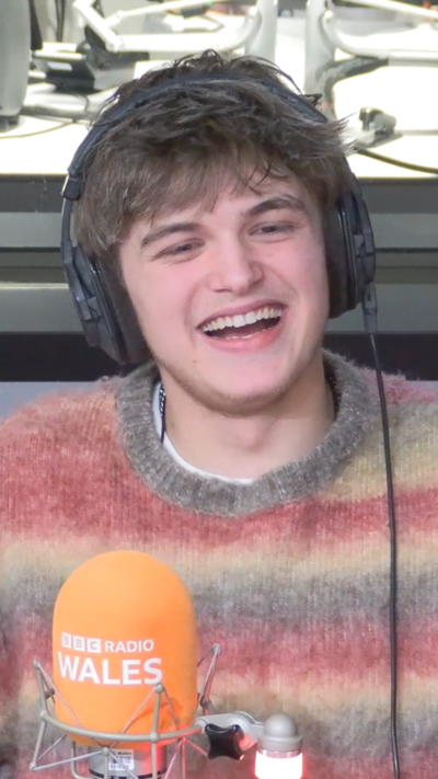 Oscar Hartland smiling in a pink grey and yellow stripy jumper