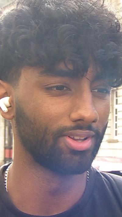 Young man with airpods in is mid speech.