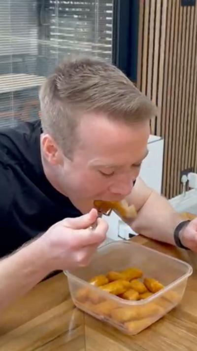 A man eating fish fingers at his dining table, trying to beat the world record for most eaten in a minute