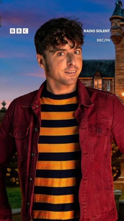 A man in a yellow and black t-shirt, wearing a red coat.