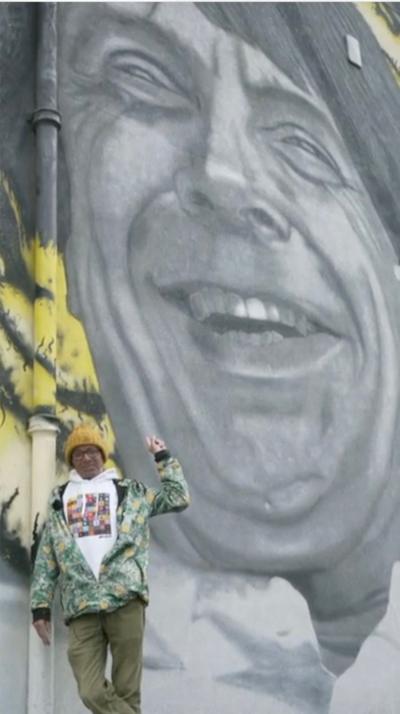 A man stood in front of the Mani Mural