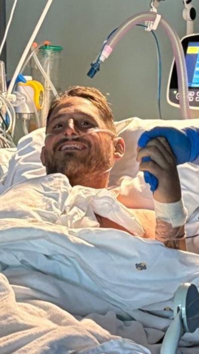 A man in a hospital bed smiling.