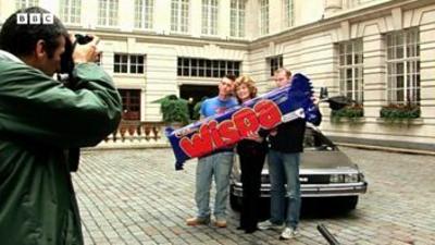 Rula Lenska flanked by two men, posing with a massive Wispa chocolate bar