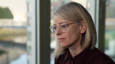 Forensic scientist Joanne Cochrane filmed in close-up profile in front of a window with a blurred view behind.