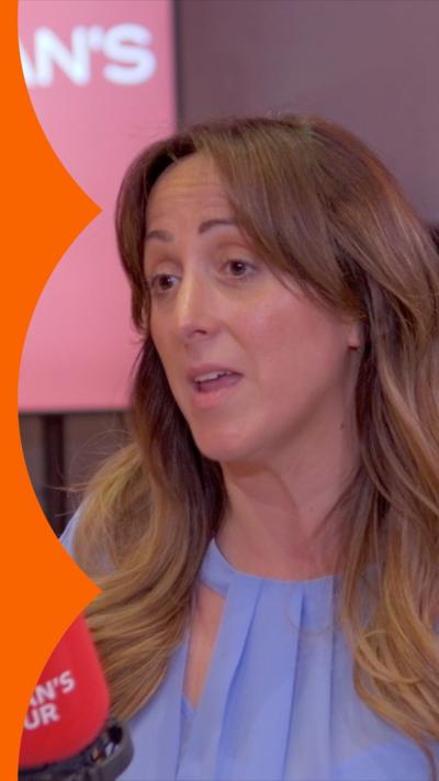 Natalie Cassidy has long wavy brown hair. She is wearing a light purple blouse.