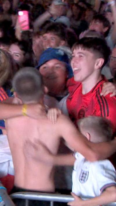 People are hugging and jumping in the air, smiling.