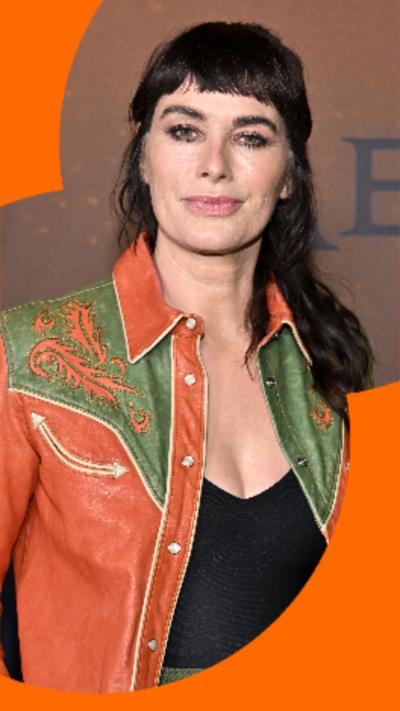 Actor Lena Headey has long dark hair and is wearing a green and orange leather jacket over a black top.