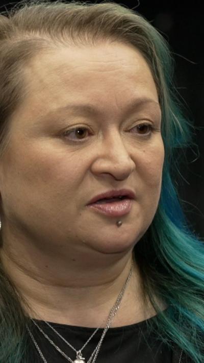 A woman with sholder length hair which is tinted bllue and green.