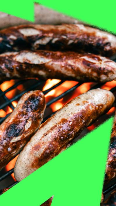 A close-up on sausages sizzling on a flaming barbecue