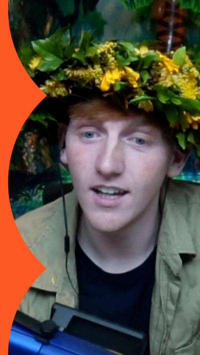 Young man wearing a leafy garland surrounded by a jungle background