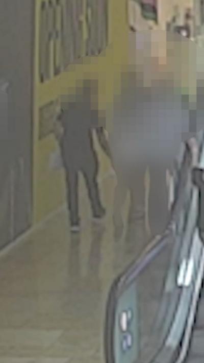 A blurry image of a man walking along an alleyway in shopping centre