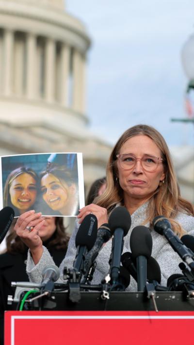 Epstein abuse survivor Annie Farmer holds up a photo of her younger self with her sister Maria Farmer.