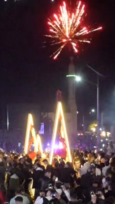 Firework above light sculpture of Christmas trees