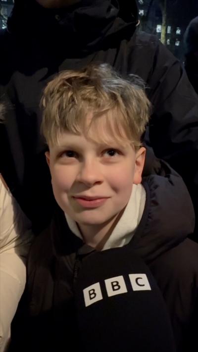 A  young boy speaking into a BBC microphone