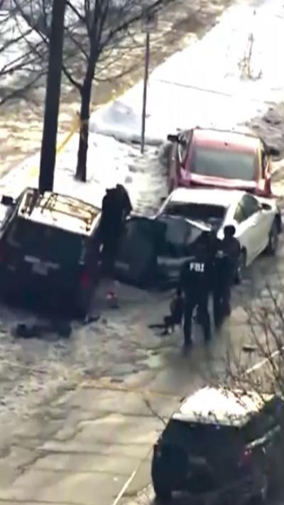 Aerial view showing FBI officers approaching three vehicles on a snowy road.