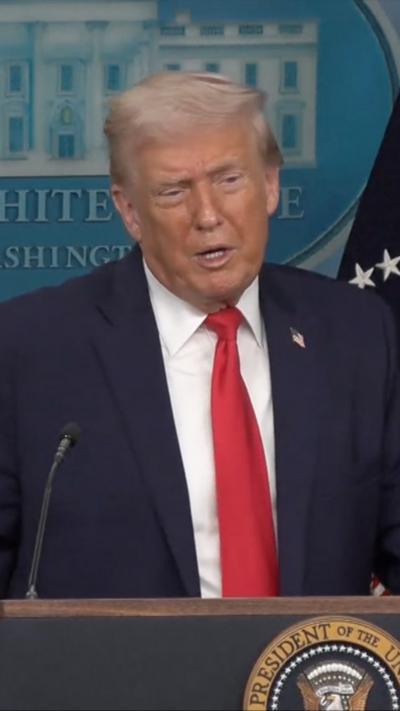 Trump behind a podium in a red tie and blue jacket