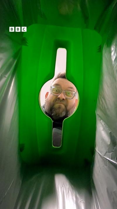 A mans face looking into a bin