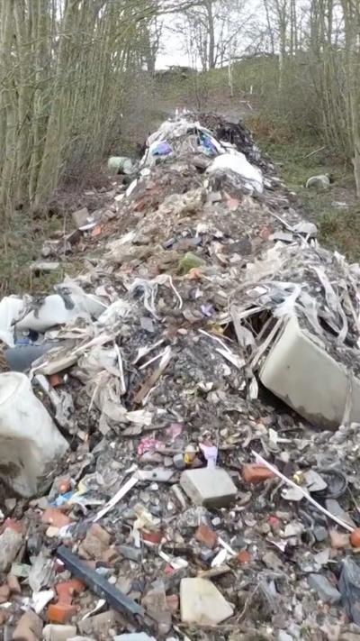 20m long pile of dumped waste near side of the road